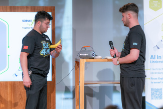 One man is holding a banana and another one is holding a microphone