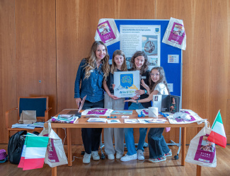 A teacher and three girls are standing behind a table