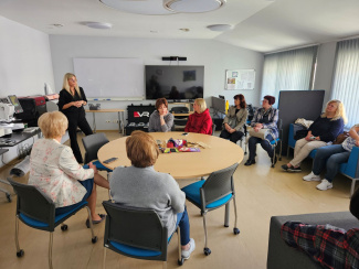 A group of teachers sitting in a circle, with a presenter standing