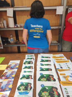 A woman with her back turned to the camera, her t-shirt reading "Teachers make the difference"