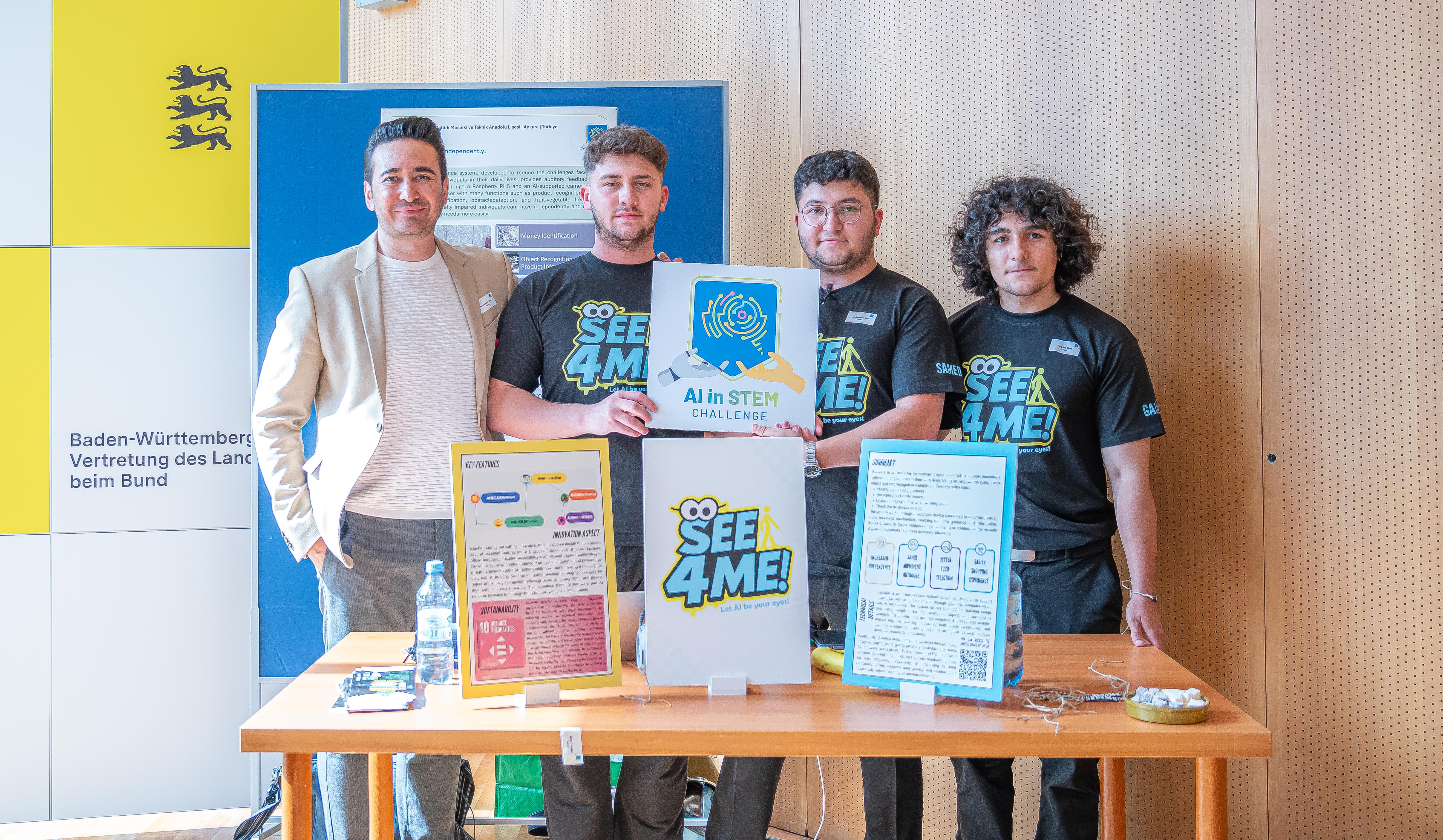 A team of one teacher and three older students at their stand during a science competition