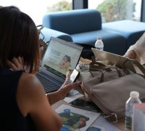 A woman seen from behind sitting at a laptop during a workshop