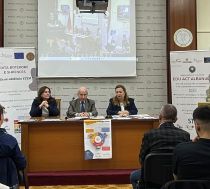 Three people at a podium table underneath a screen