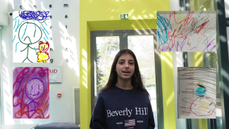 A student between four colourful drawings by young children