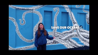 A student in front of a blue wall with stencil graffiti of a giant octopus