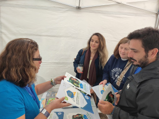 A woman handing our flyers at a stand in a science fair
