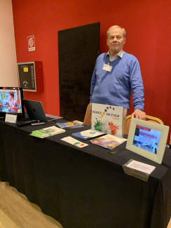 A man standing behind a stand with info materials during a science conference