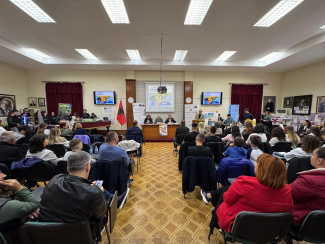 A conference room with full attendance seen from the back of the audience