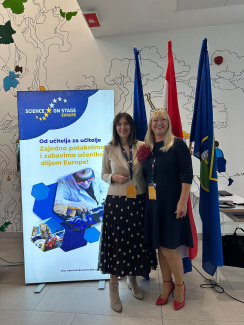 Two women next to flags and a banner for Science on Stage Croatia
