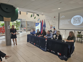 Six panelists sitting at a table in a conference venue