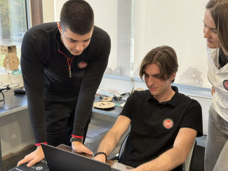 Two students and their mentor looking at a laptop screen