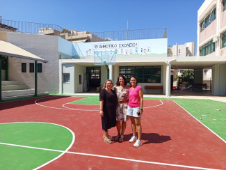 3 teachers on the track field in front of a Greek school