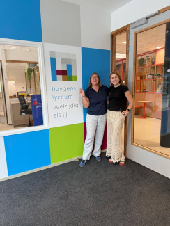 Two teachers next to the logo of Huygens Lyceum