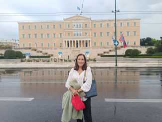 A woman standing in front of a representative building with a portico entrance